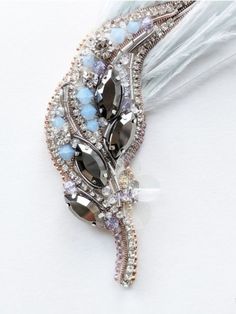 a close up of a brooch with beads and feathers on white background, showing the beading