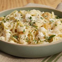 a bowl filled with pasta and parmesan cheese on top of a wooden table