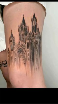 a tattoo on the back of a woman's thigh with an image of a castle