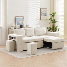 a living room with a white couch and two ottomans on the floor in front of a potted plant