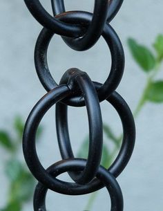 a close up of a metal chain hanging from a planter with green leaves in the background