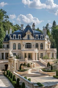 a large white mansion with many windows and balconies on the roof, surrounded by trees