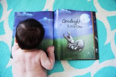 a baby is reading a book to a little bunny