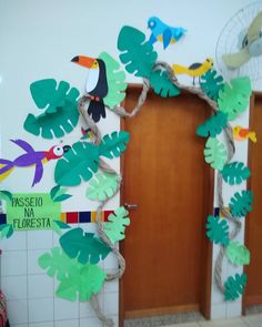 some paper birds and leaves are hanging on the wall in front of two wooden doors