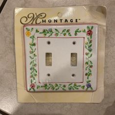 a decorative light switch plate cover with flowers and vines on it, sitting on a table