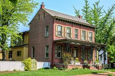 a red brick house sitting on top of a lush green field