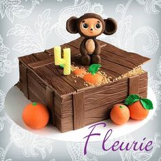 a cake made to look like a box with a monkey on top and oranges around it