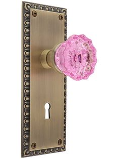 a pink glass door knob on an ornate brass finish