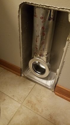 an open toilet in the corner of a bathroom with tile flooring and walls that have been torn off