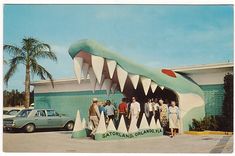 a group of people standing in front of a building with a giant alligator's mouth