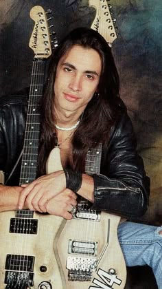 a young man with long hair and leather jacket holding an electric guitar in front of his face