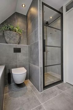 a bathroom with a toilet, shower and planter in the corner on the wall