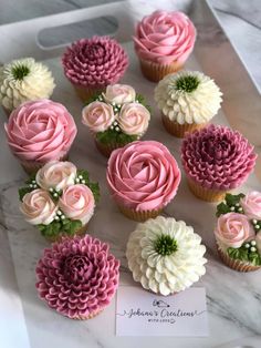 cupcakes decorated with pink and white flowers on top of a marble countertop