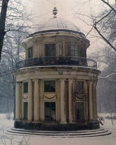 an old round building in the middle of a snow covered park with lots of trees