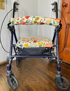 a blue walker with flowers on it sitting in the middle of a wooden floor next to a door