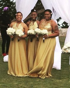 three women in gold dresses standing next to each other under a white canopy with flowers on it