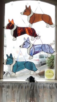 three glass dogs hanging from a window sill in front of a white table cloth