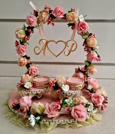 a cake stand with cupcakes and flowers on it, decorated with a monogram