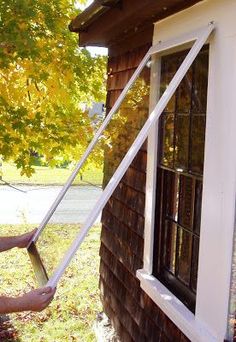 a man is cleaning the windows outside of a house with a window roller and brush