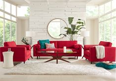 a living room filled with red couches and chairs next to a round mirror on the wall