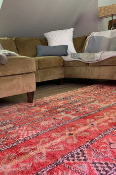 a living room filled with furniture and rugs on top of a wooden floor next to a window