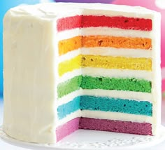 there is a multi layer cake with white frosting on the bottom and rainbow colored layers