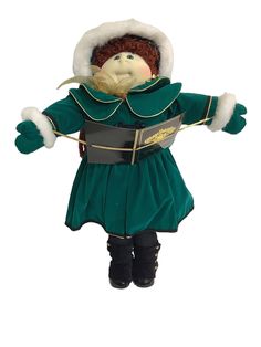 a stuffed doll in a green dress and hat with arms outstretched, wearing black boots