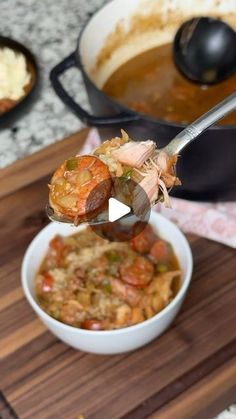 a person spooning food out of a bowl on top of a wooden cutting board