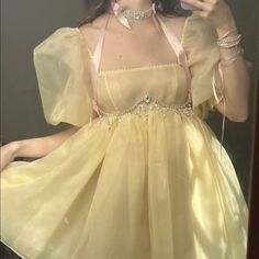 a woman taking a selfie in a mirror wearing a yellow dress and holding a cell phone