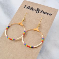 Your soon-to-be favorites, these small gold beaded hoops (available in 22 exclusive patterns) are perfect for day, night and well, everything in between. Ivory beads with rainbow colors gold-plated hoop and hooks lead-free and nickel-free glass seed beads plastic earring back 1.25" in diameter and overall length is 2" from top of hook packaged on a hand-stamped kraft earring card in a clear resealing bag Everyday Colorful Beaded Small Hoop Earrings, Rainbow Beaded Small Hoop Earrings, Multicolor Beaded Small Hoop Earrings, Rainbow Hoop Beaded Earrings With Colorful Beads, Rainbow Colorful Beads Hoop Earrings, Earring Card, Plastic Earrings, Rainbow Beads, Earring Cards