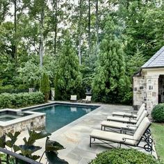 an outdoor pool with lounge chairs and trees in the background, surrounded by greenery