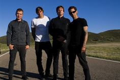 four men standing in the middle of an empty road