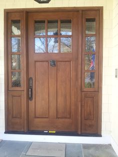 a wooden front door with two sidelights and glass panels on the top half of it