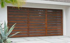 an image of a garage door with wood slats on the side and palm trees in front