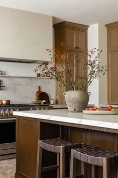 a kitchen with wooden cabinets and white counter tops, two stools in front of the island