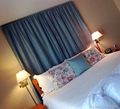 a bed with white sheets and blue curtains