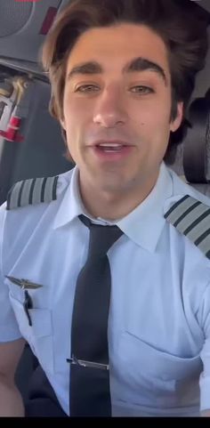 a man in uniform is sitting in the back seat of an airplane and making a funny face