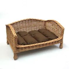 a wicker dog bed with brown pillows on the top and bottom, in front of a white background