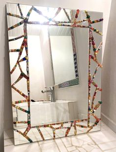 a bathroom mirror that has been decorated with colorful beads and lights on the bottom half