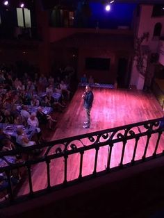 a man standing on top of a wooden floor in front of an auditorium filled with people