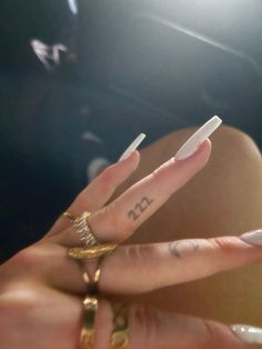 a woman's hand with two fingers that have the letter m on it, and an arrow tattoo