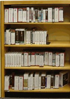 a book shelf filled with lots of books on top of wooden shelves next to a wall