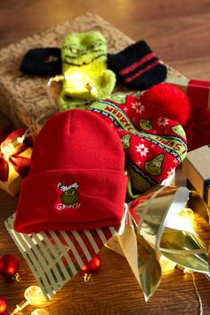 several hats and gifts on a table with christmas lights around the edges, including one red beanie