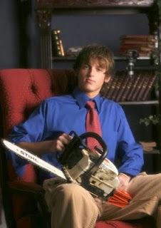 a man sitting in a chair holding a chainsaw