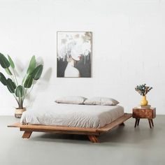 a bed sitting in the middle of a room next to a table and potted plant