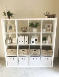 a white bookcase with baskets and pictures on it