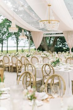 the tables are set with white linens and chandeliers hanging from the ceiling