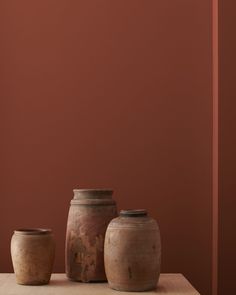 three vases sitting on top of a table next to each other in front of a pink wall