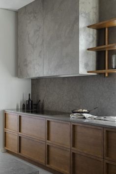 a modern kitchen with wooden cabinets and marble counter tops, along with shelves on the wall