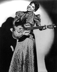 an old black and white photo of a woman holding a guitar